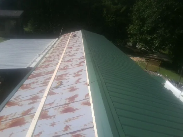 Old rusted panels beside newly installed green metal roofing — Wind Damage Roof Repair by Roofing Brothers in Fulton