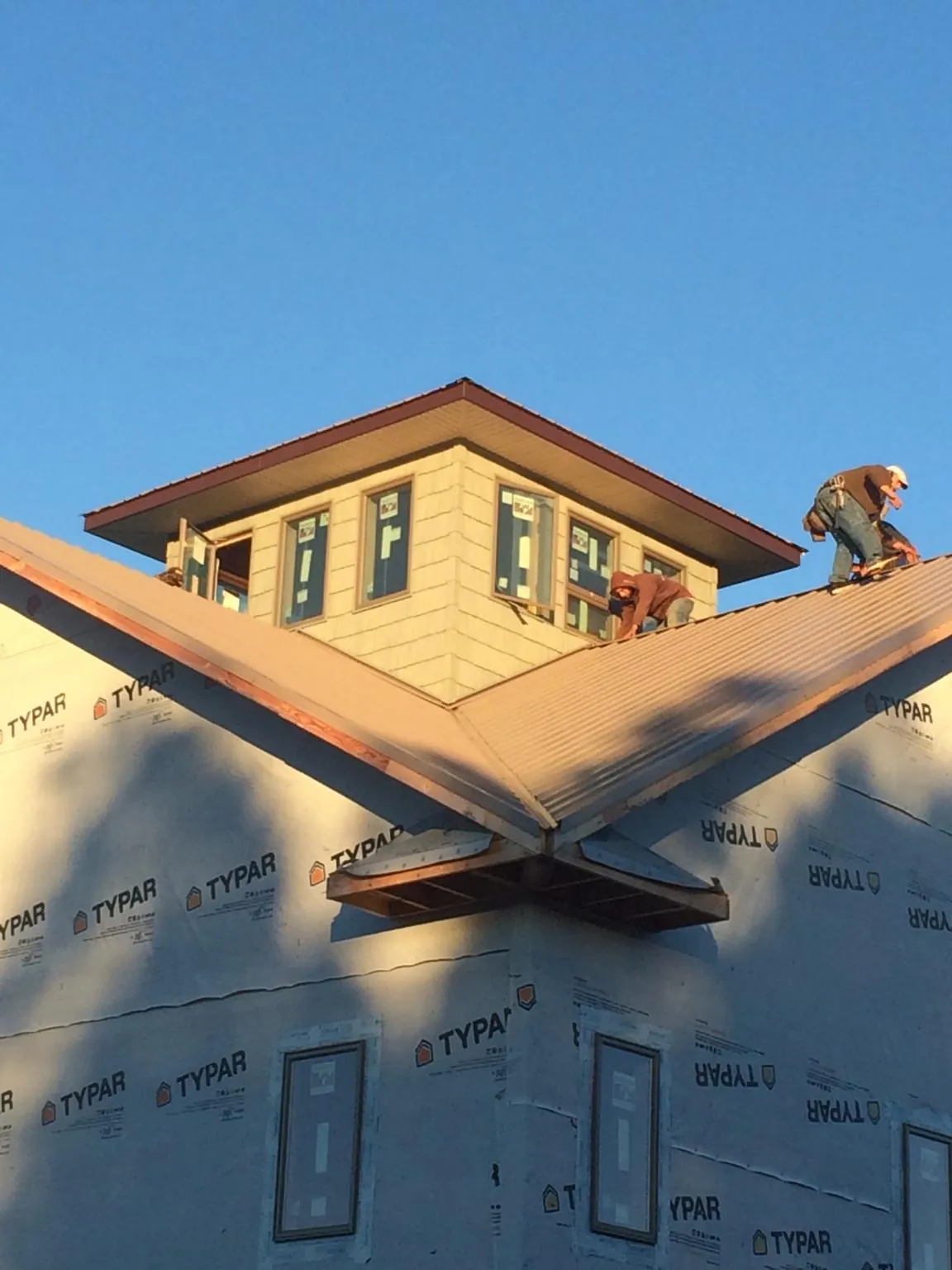 Roofers working around a rooftop cupola on a new metal roof at sunset — Roof Waterproofing in Fulton by Roofing Brothers